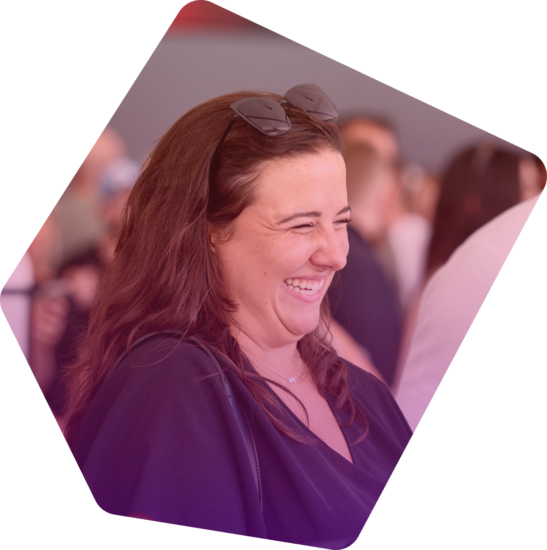 Woman with brown hair and sunglasses smiling warmly at a networking event
