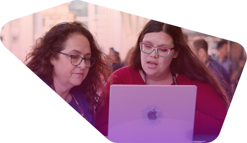 Two women with glasses collaborating on a laptop at a conference