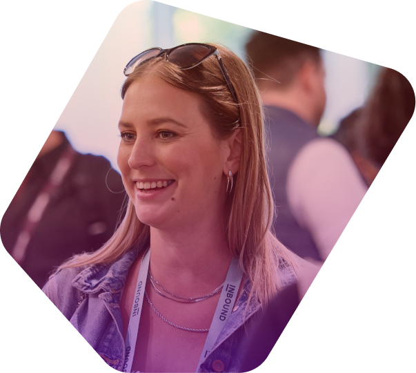 Smiling woman with blonde hair and sunglasses at conference event wearing lanyard