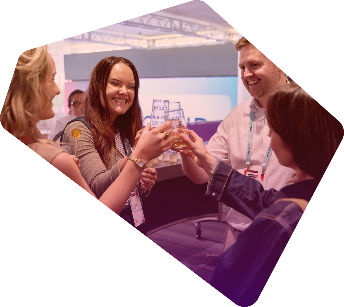 Three smiling conference attendees with name badges toast with beer glasses