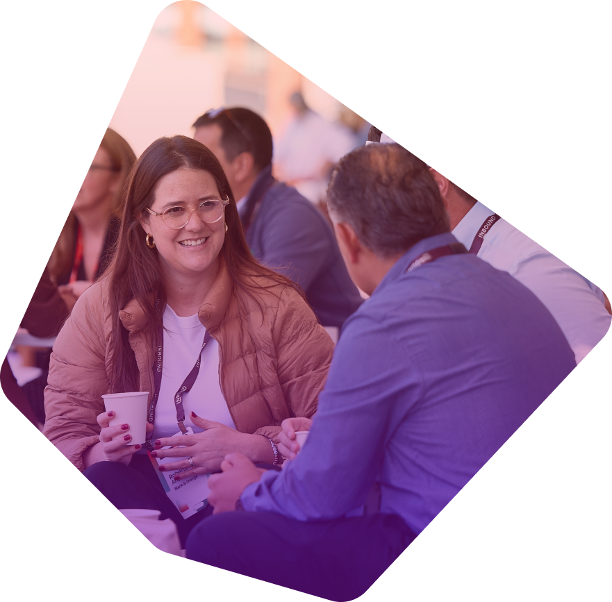 Woman with glasses smiling while talking to man at networking event