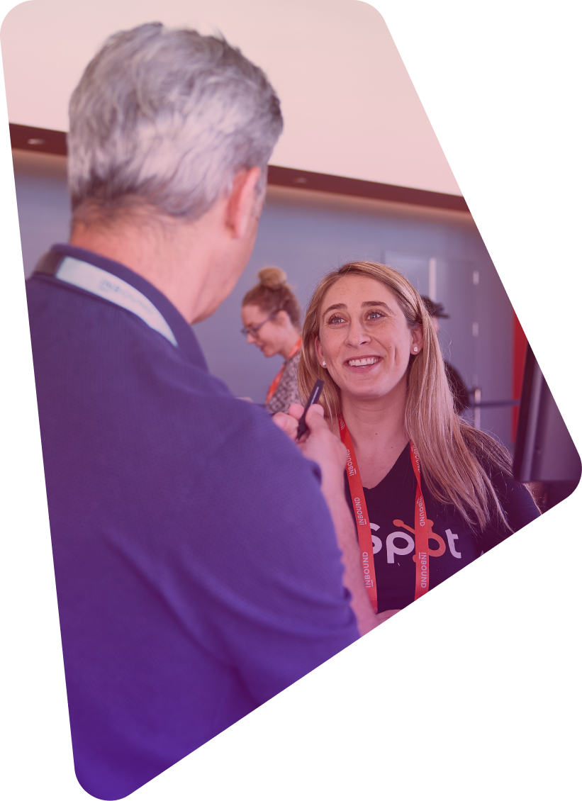 Woman with red lanyard smiling while talking to man in suit at conference