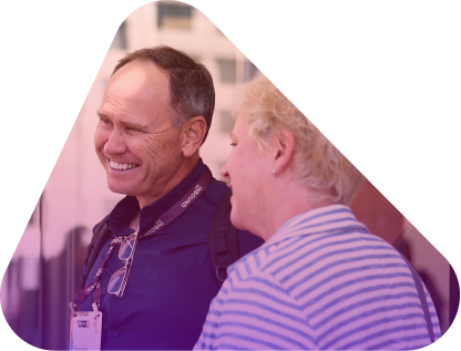 Two men smiling and talking at a conference, one wearing a lanyard