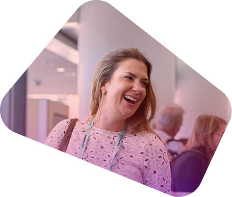 Smiling woman with blonde hair in white patterned top at conference